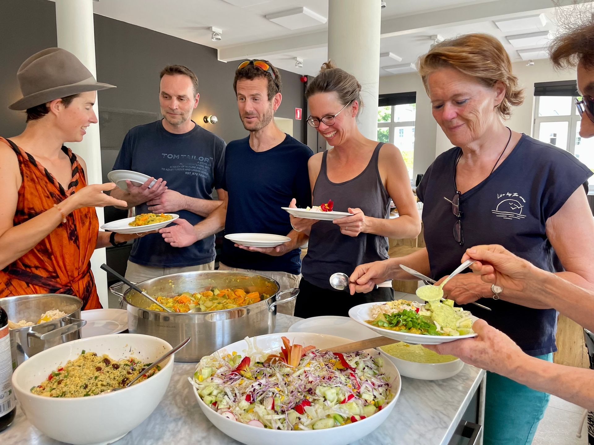 Group of people serving themselves from a buffet with various salads and dishes at a casual gathering.