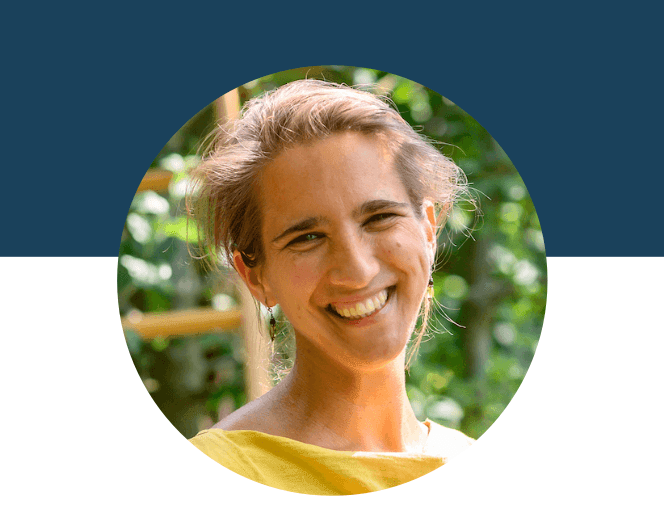 Smiling person in a yellow top with greenery in the background.